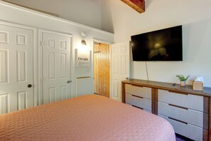 Een slaapkamer met een bed, een dressoir, een aan de muur bevestigde televisie en een deur met een bordje.