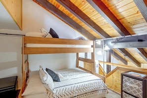 Ein Etagenbett mit Holzgestell und einer Matratze mit gemusterten Bettbezügen.