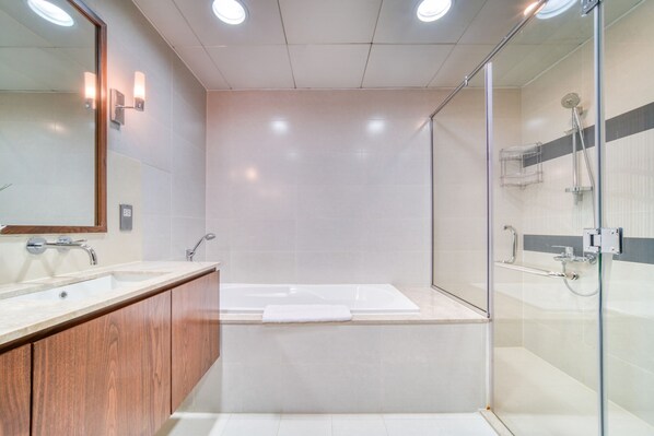 A modern bathroom with a glass-enclosed shower, a wooden vanity, and a large mirror.