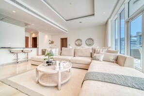 Una sala moderna con un sofá seccional, una mesa redonda de centro y vistas de la ciudad a través de grandes ventanales.