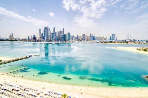 A coastal cityscape with a marina, beach, and modern skyline.