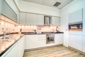 Une cuisine moderne avec des armoires blanches, des appareils en acier inoxydable et un plancher en bois.