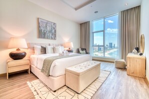A modern hotel room with a large bed, two bedside tables, a view of the city, and a large window.