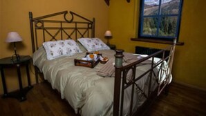 A bedroom with a wooden bed, two bedside tables, a window with a view, and a lamp on each table.