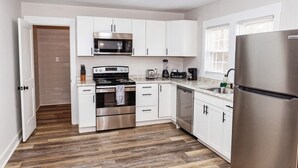 A modern kitchen with white cabinets, stainless steel appliances, and a wooden floor. - Salem Road Ranch | 3 BR w/ Outdor Firepit and Backyard (Lincolnton)
