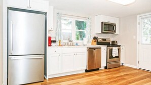 Une cuisine moderne avec des meubles blancs, des appareils en acier inoxydable et un plancher en bois.