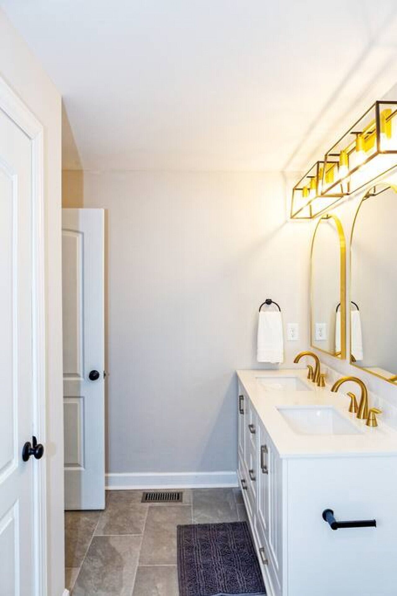 A bathroom with a white vanity, gold fixtures, and a large mirror.