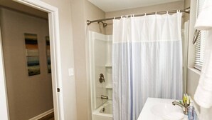 Une salle de bain avec une douche, un lavabo et un porte-serviettes.