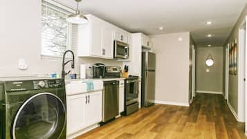 Una cocina moderna con armarios blancos, electrodomésticos de acero inoxidable y una lavadora.