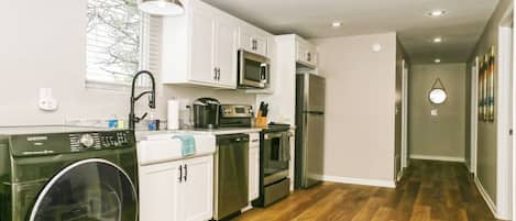 A modern kitchen with white cabinets, stainless steel appliances, and a washing machine.