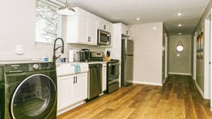 Une cuisine moderne avec des meubles blancs, des appareils en acier inoxydable et un lave-linge.