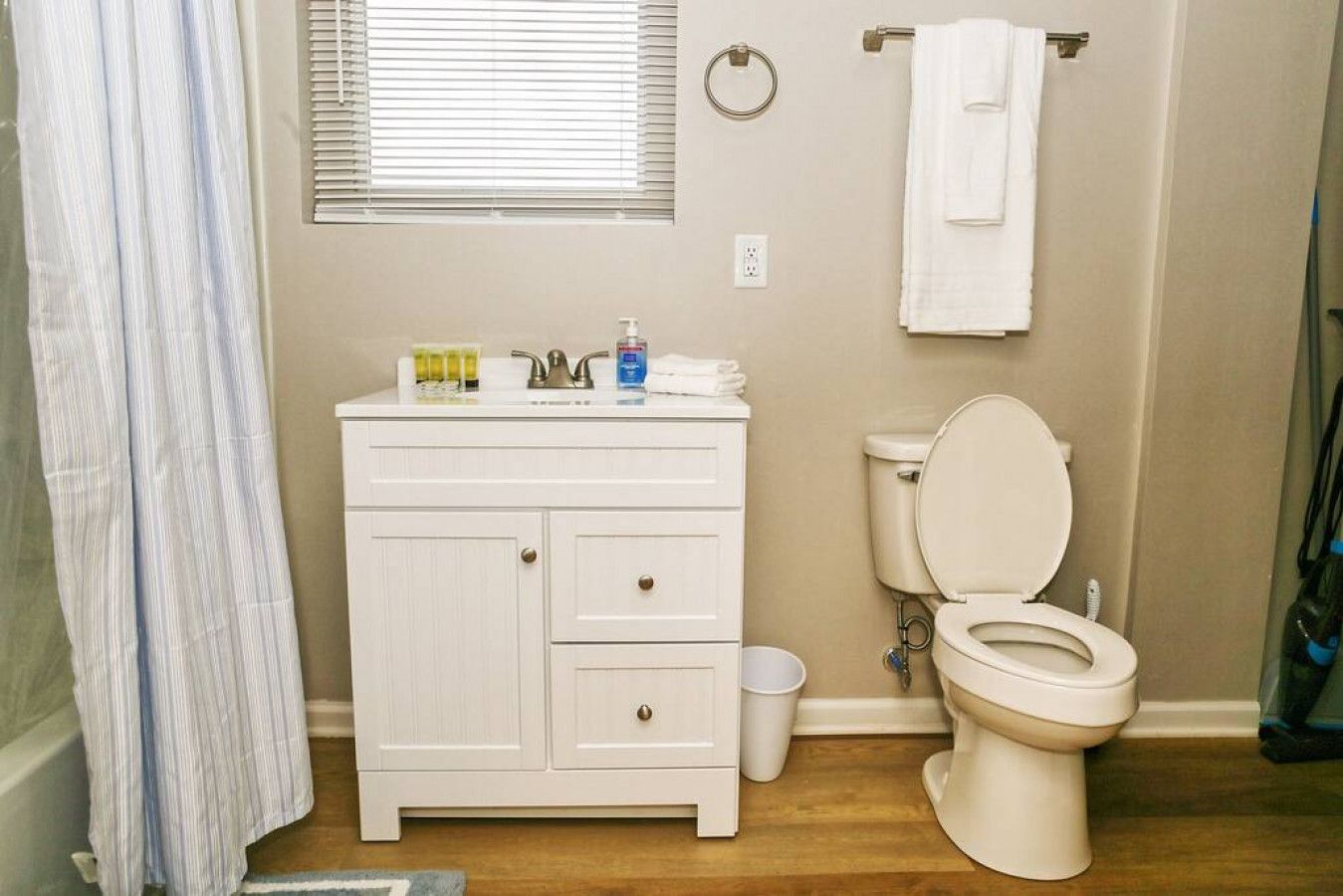 Une salle de bain avec un meuble-lavabo blanc, des toilettes et un rideau de douche.