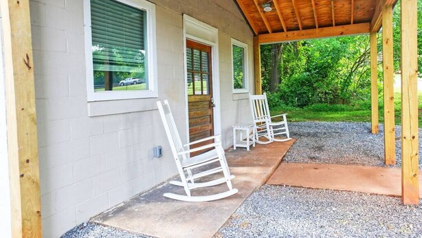 Une véranda couverte avec un plafond en bois et une chaise berçante.