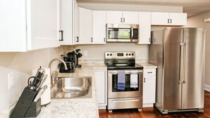 A modern kitchen with white cabinets, stainless steel appliances, a sink, and a countertop.