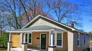 A single-story house with a front porch, a chimney, and a small front yard.