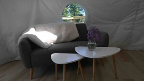 A cozy room with a grey sofa, a white table, and a vase with purple flowers. - Dome 1 - Luxury Dome at Come Spring Farm (Union)