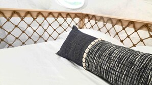 A bed with a white mattress, a black and beige pillow, and a wooden headboard with a woven design. - Dome 1 - Luxury Dome at Come Spring Farm (Union)