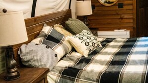 A cozy bedroom with a checkered bedspread, a wooden headboard, and a mirror on the wall.