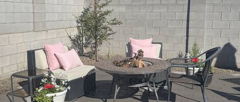 Une terrasse extérieure avec une table ronde, deux chaises, un canapé avec des coussins et des plantes en pot.