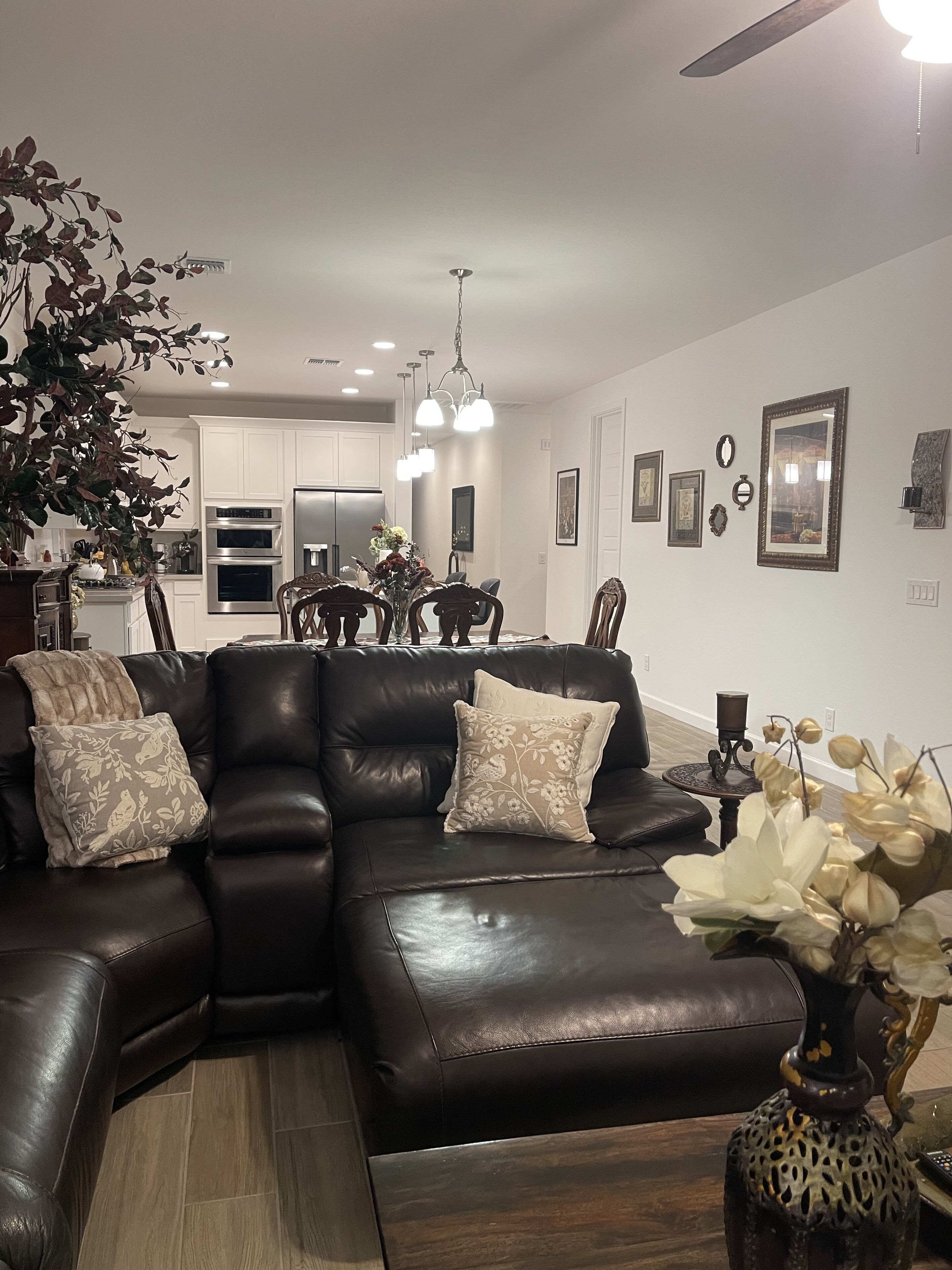 A modern living room with a sectional sofa, a dining area, and a kitchen in the background.