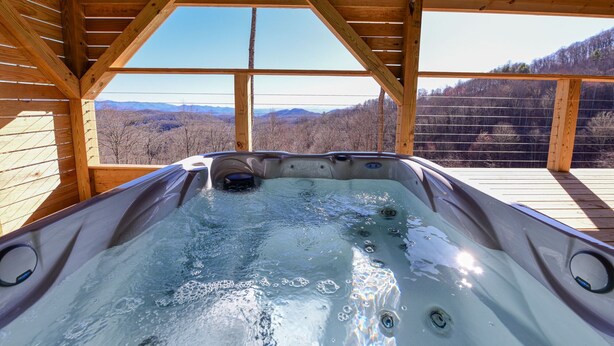 Un jacuzzi con interior de madera y vistas a las montañas.