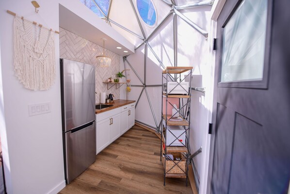 Una cocina moderna con refrigerador de acero inoxidable, encimera de madera y salpicadero con motivo de espiga.