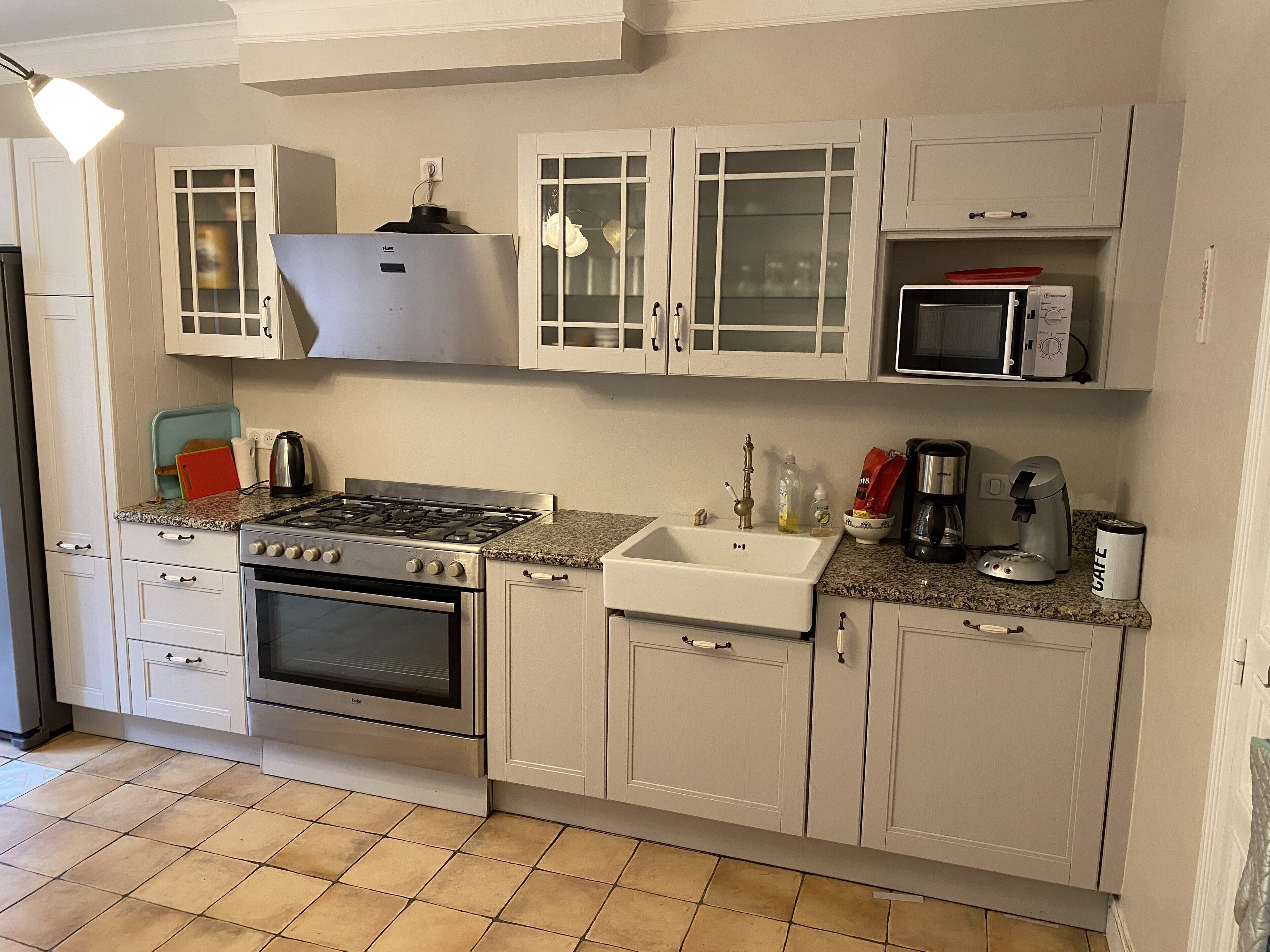 A kitchen with white cabinets, a stove, a sink, and a microwave.
