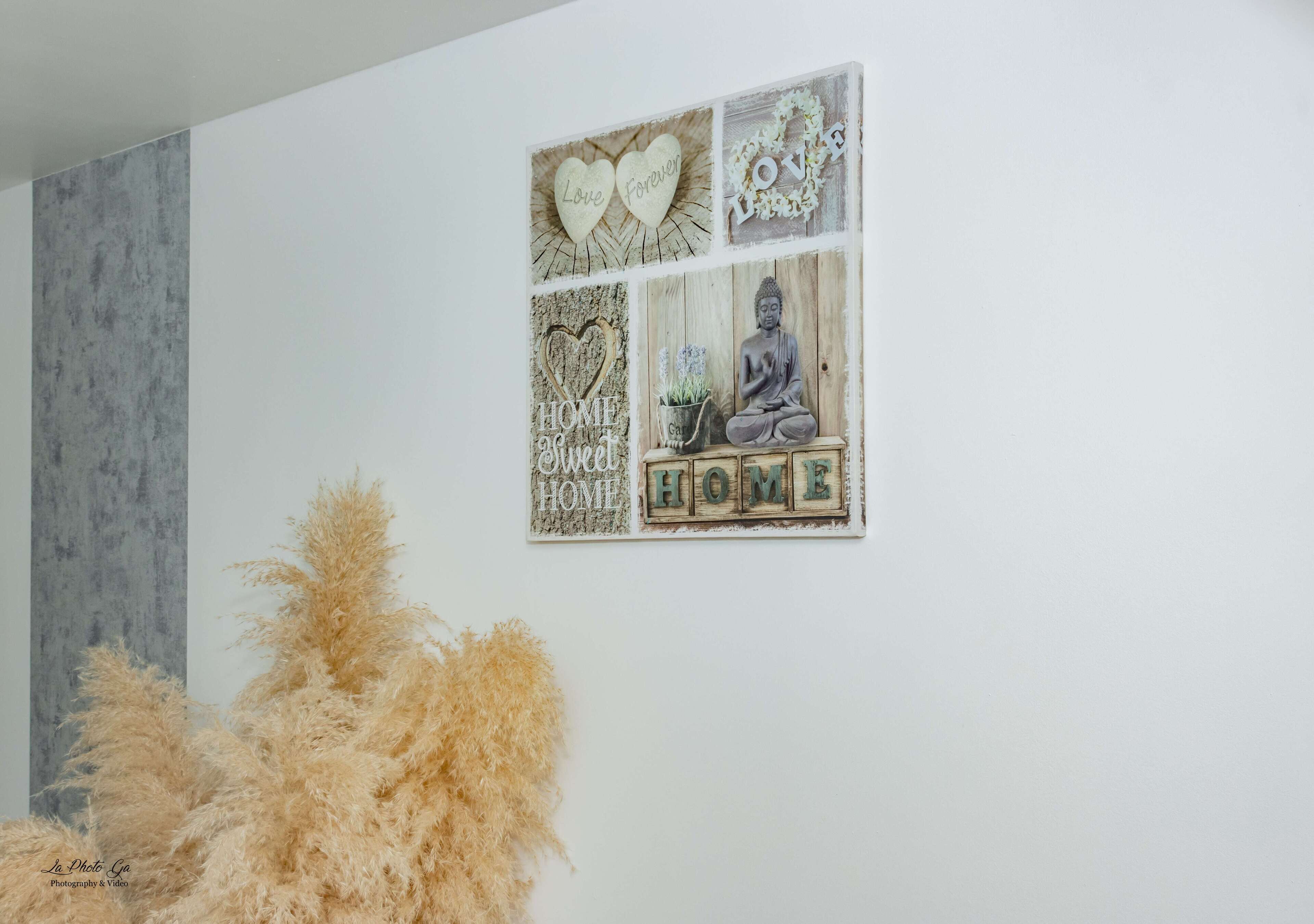 Un mur orné d’un panneau décoratif représentant une statue de Bouddha, des cœurs et les mots « Love Forever » et « HOME ».