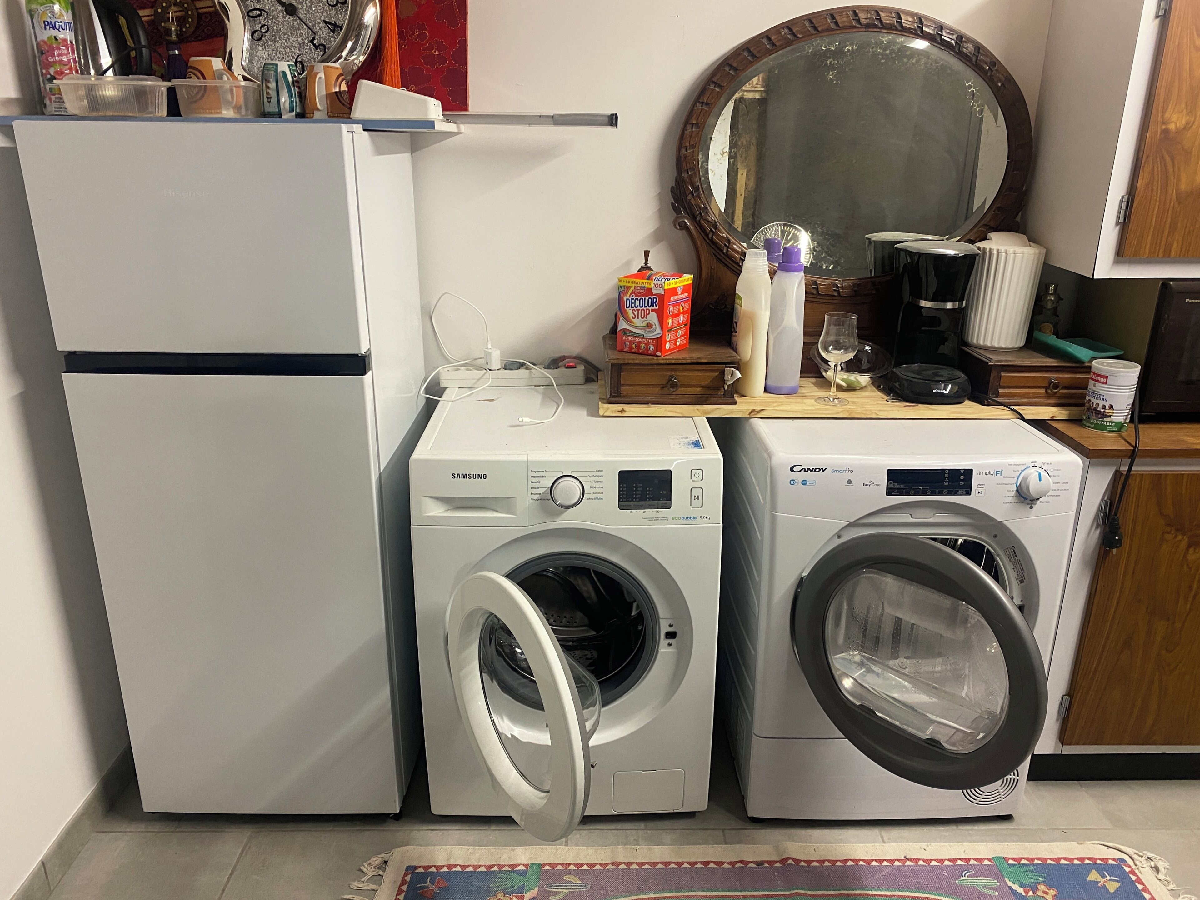 Eine kleine Küche mit Kühlschrank, Waschmaschine und Mikrowelle.