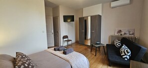 Een hotelkamer met een bed, een bank, een bijzettafeltje, een stoel en een garderobe.