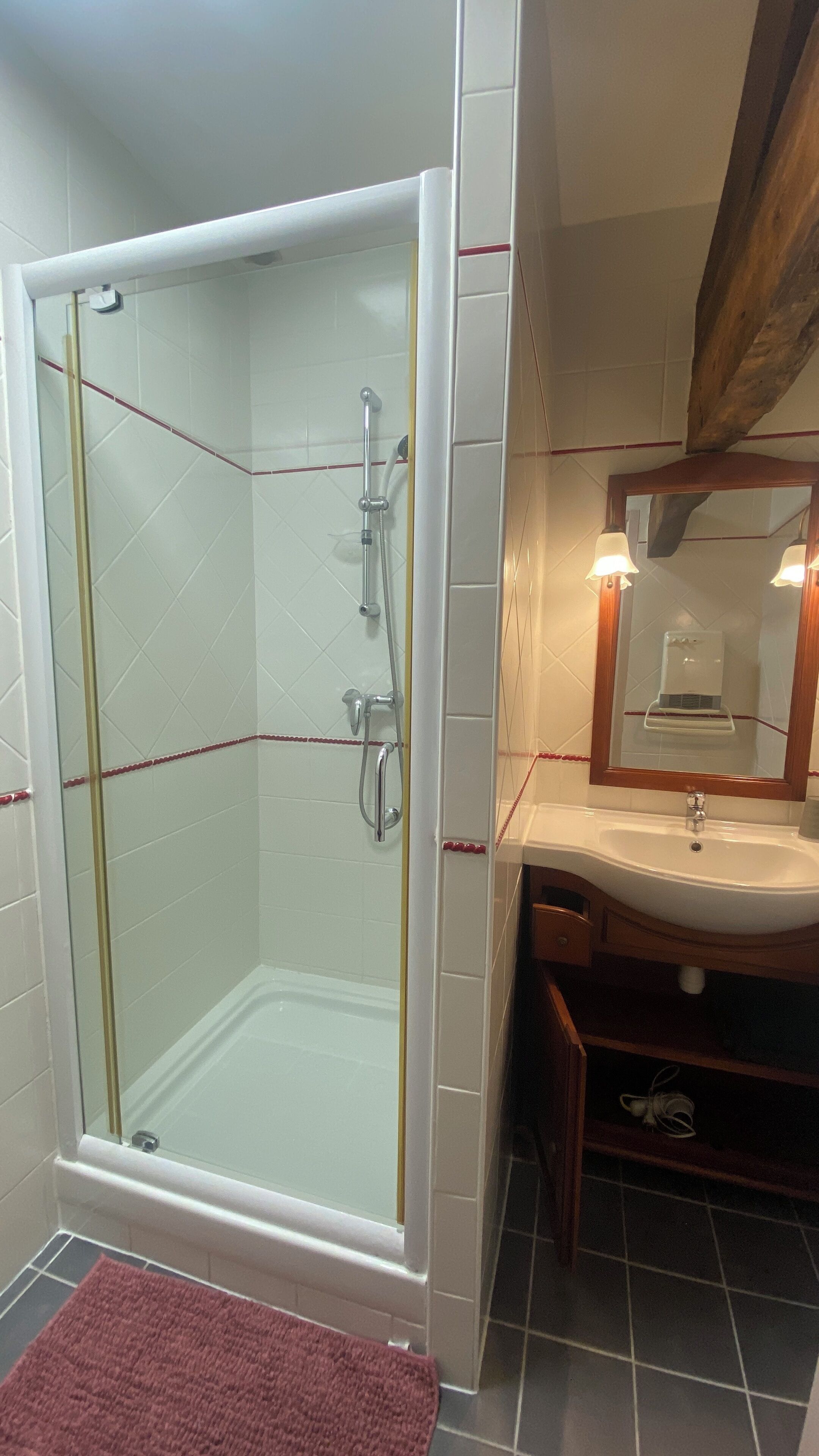 A bathroom with a glass-enclosed shower, a sink with a mirror, and a wooden vanity.