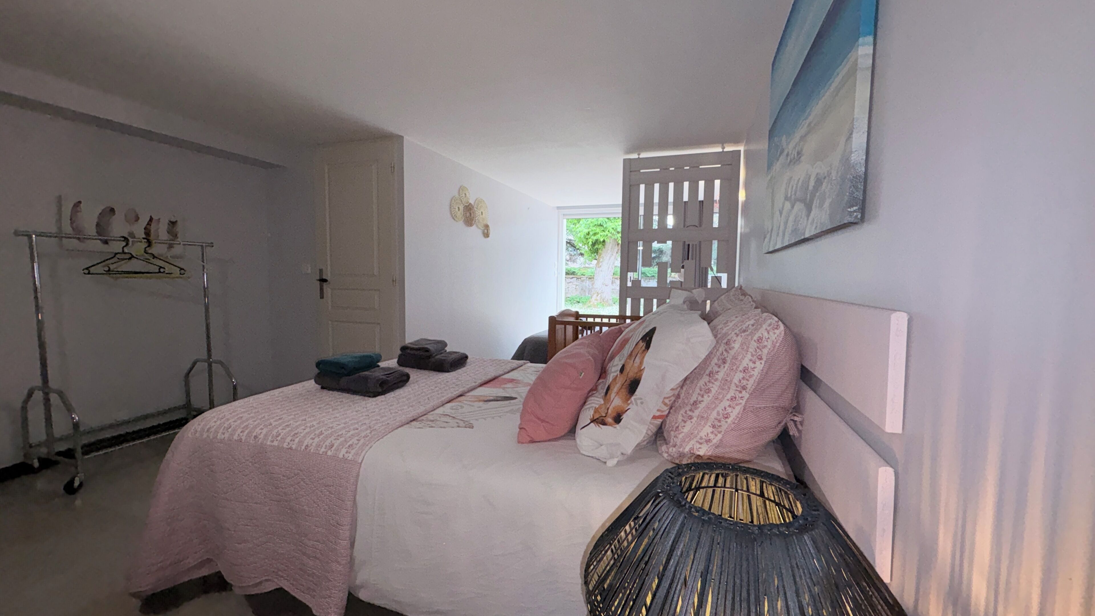 Een slaapkamer met een bed, een kledingkast, een kapstok en een raam.