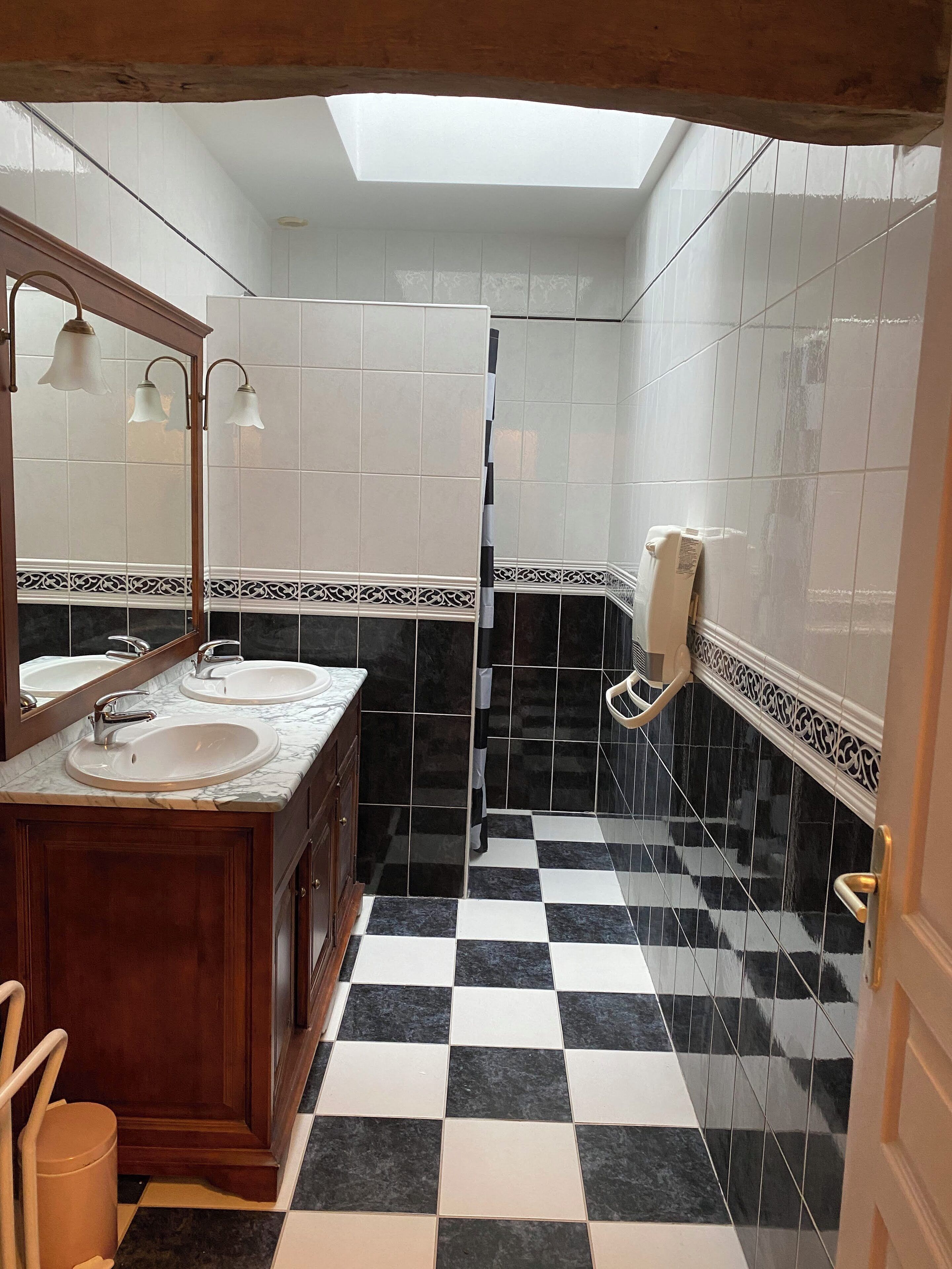 Baño con dos lavamanos, un espejo y cabina de ducha.