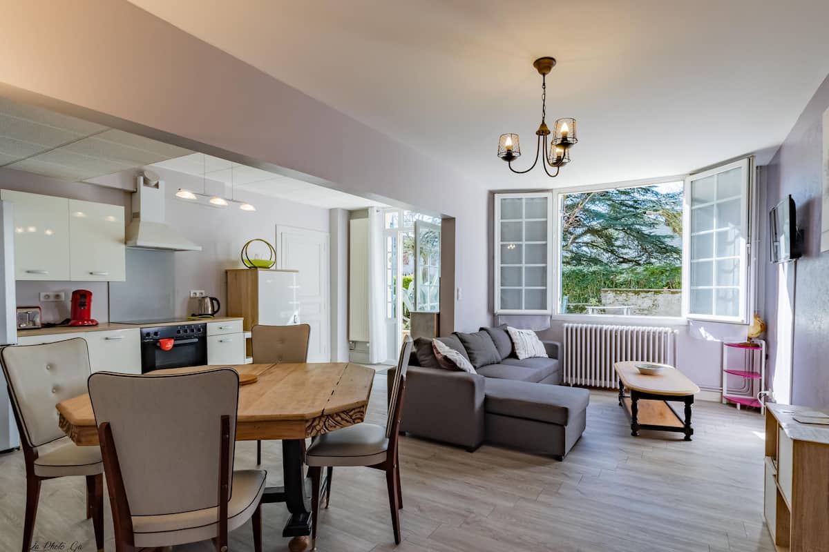 A modern kitchen with white cabinets, a dining table with chairs, a sofa, and a small table with a bowl.