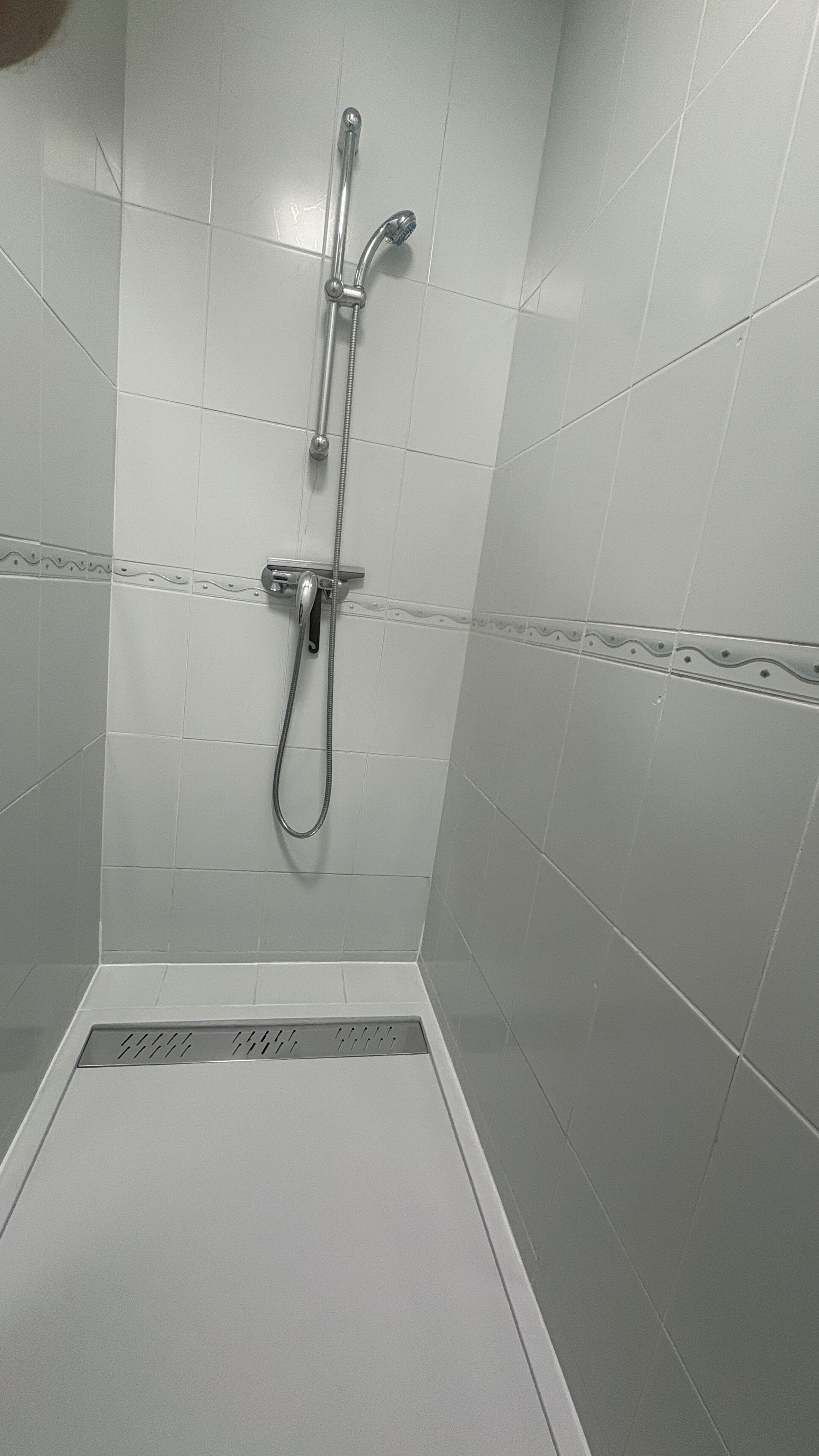A shower with a handheld showerhead and a fixed showerhead.