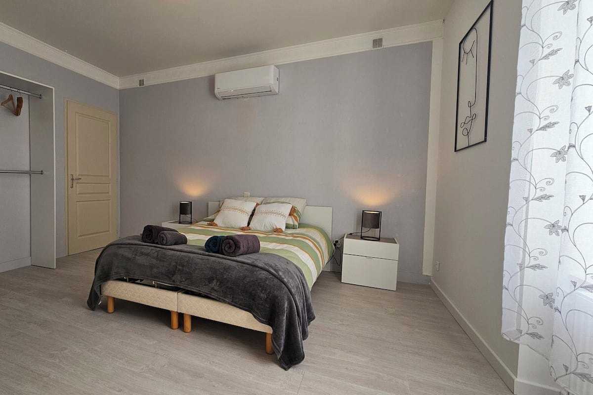 A bedroom with a bed, bedside tables, a wardrobe, and a wall-mounted air conditioner.