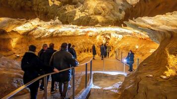 Visitas turísticas exploram uma gruta por meio de uma passarela metálica.