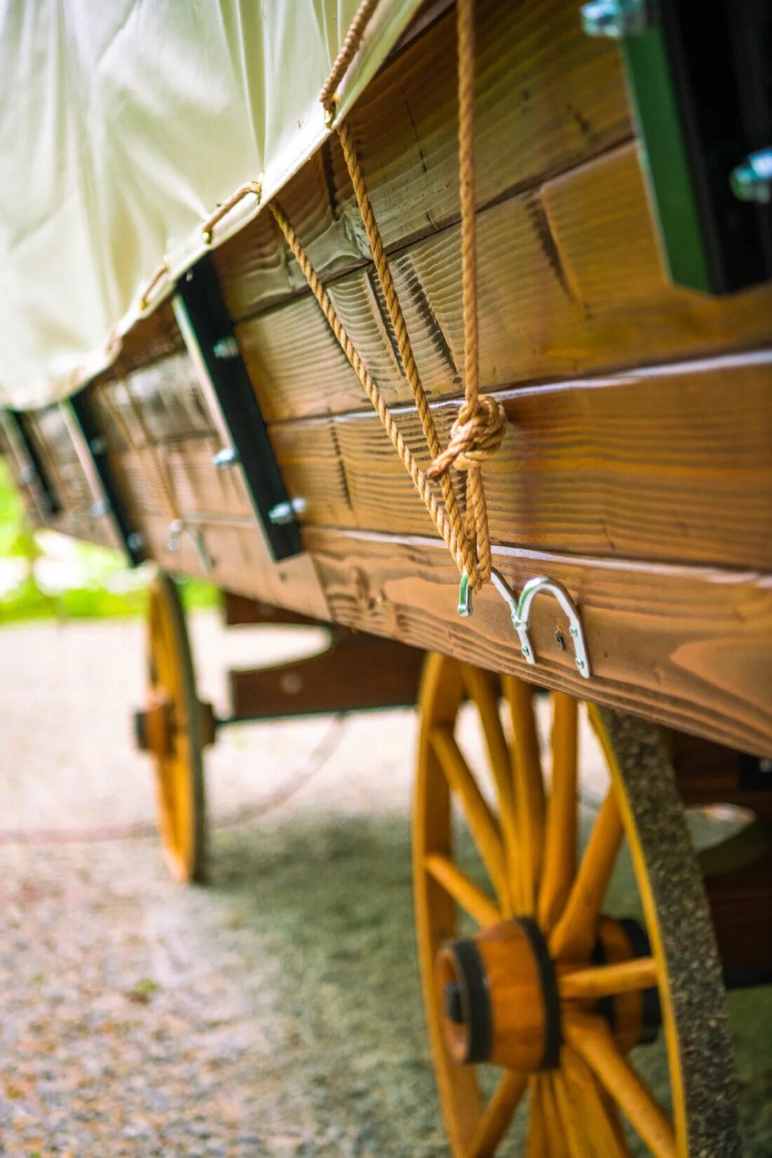 A wooden carriage with a rope tied to a metal ring, a wooden wheel, and a metal bracket.