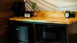 A compact kitchen with a wooden countertop, a black refrigerator, a microwave, a coffee maker, and a clock. - WAGON 1 in The Graystone Ranch in the Woods (Arcanum)