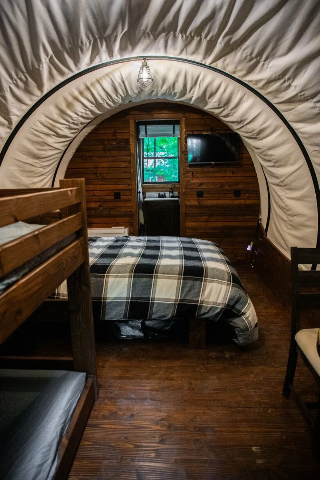 A cozy tent with a bed, a small table, and a TV.