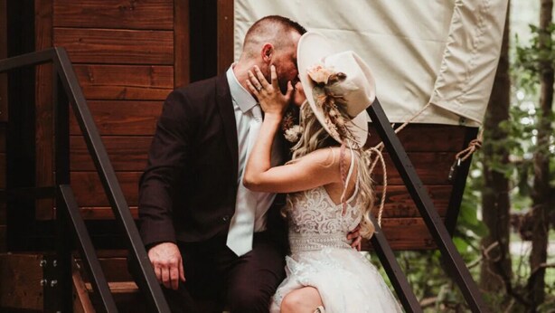 A couple embracing on wooden steps with a rustic backdrop. - WAGON 1 in The Graystone Ranch in the Woods (Arcanum)