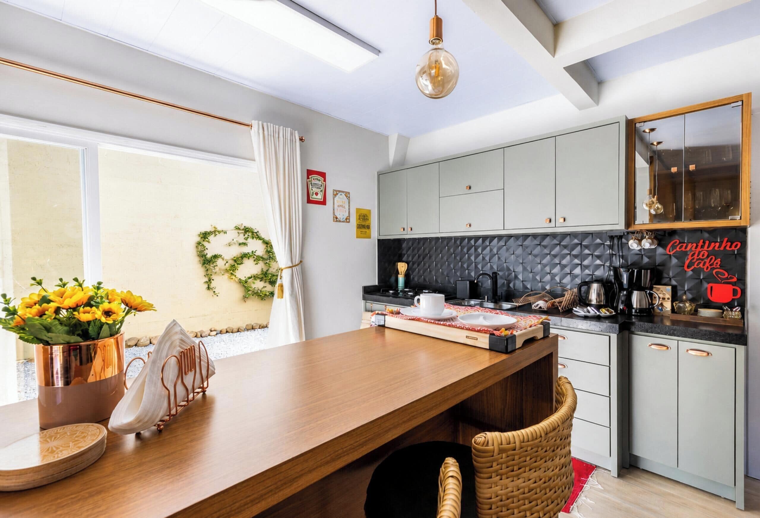 Una cocina moderna con encimera de madera, salpicadero negro y una lámpara colgante.