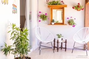 A room with two white wireframe chairs, a small wooden table, and a mirror on the wall. - Ibira Oásis - Imbituba - SC (Imbituba)