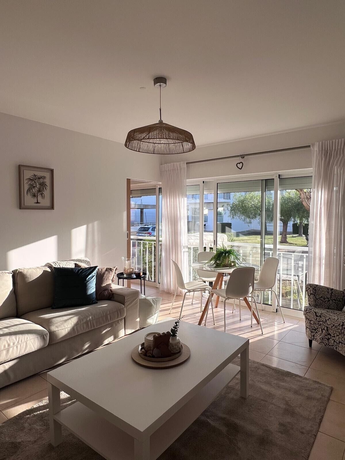 A modern living room with a sofa, a coffee table, and a dining area with chairs and a table.