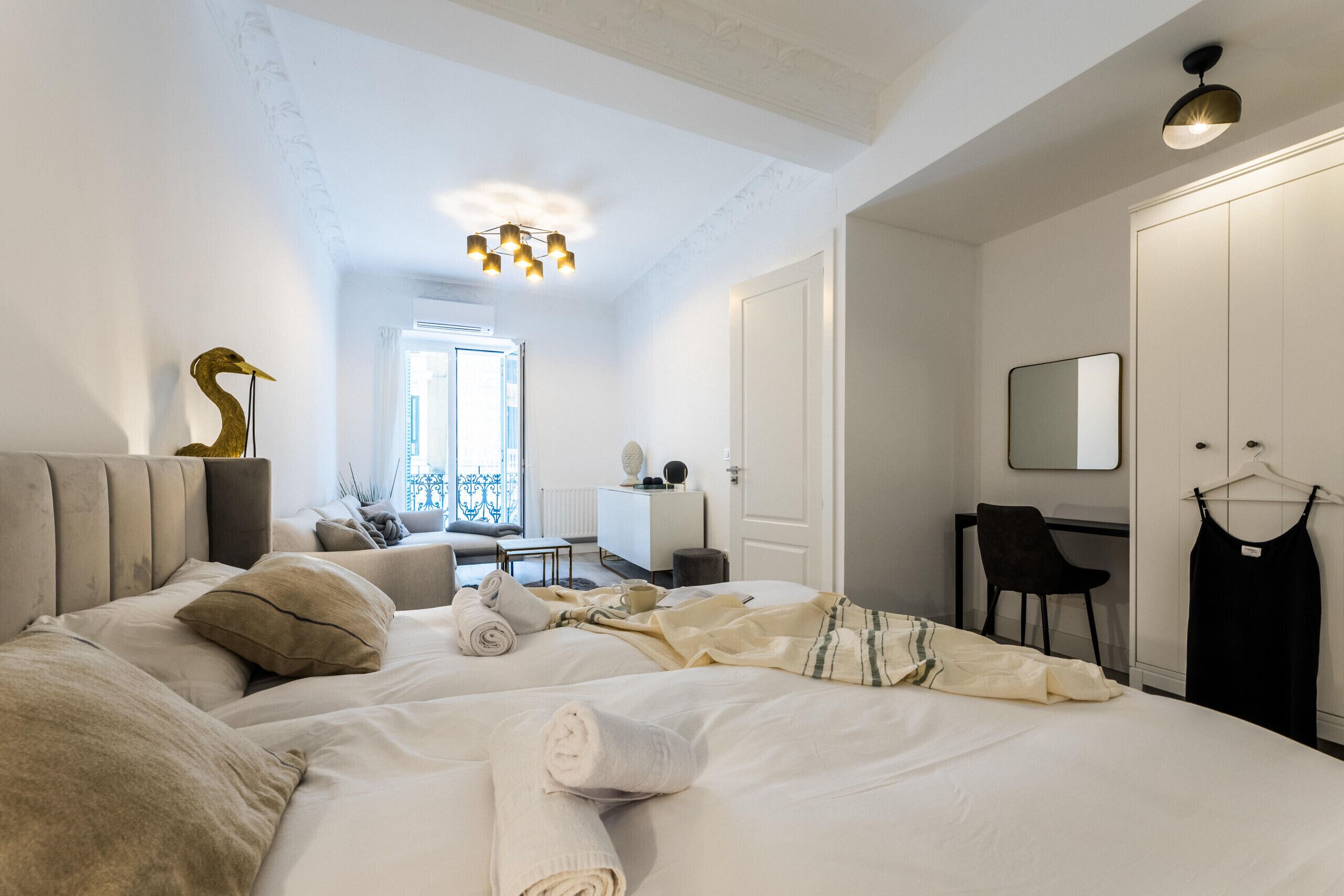 Habitación de hotel con cama, escritorio, silla, armario y un vestido colgado.