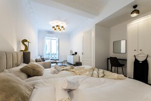 A hotel room with a bed, a desk, a chair, a wardrobe, and a hanging dress. - BALEA SUITE APARTMENT (San Sebastián)