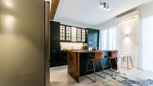 Une cuisine moderne avec des meubles de couleur sombre, un îlot central en bois et un coin bar avec des tabourets.