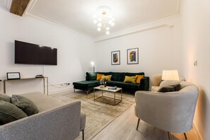 A modern living room with a flat-screen TV, a green sofa, a coffee table, and a lamp. - BALEA SUITE APARTMENT (San Sebastián)