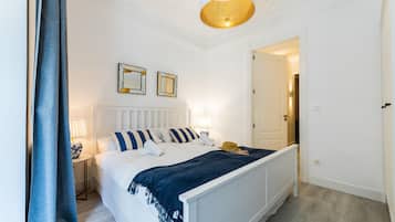 Una camera da letto ordinata con un letto, lampade ai comodini, uno specchio e una porta che dà su un'altra stanza.