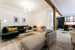 A modern living room with a sectional sofa, a coffee table, and a dining area with a kitchen in the background.
